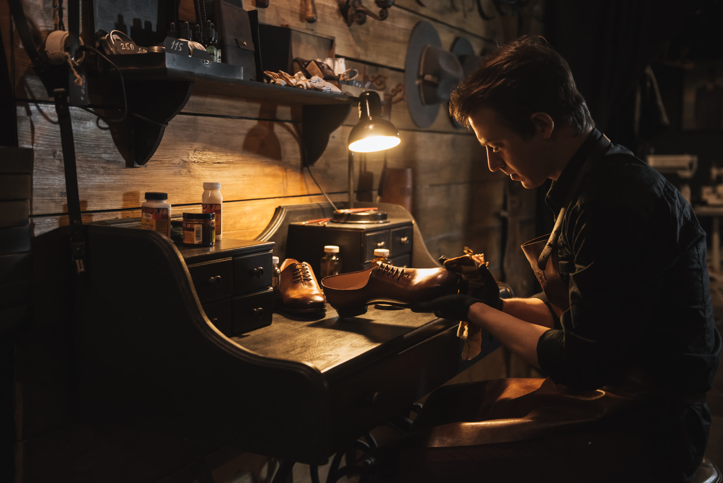Artisan working at a bench under a lamp in a dark craft workshop
